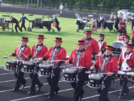 The Muchachos Drum Line parading in front of the stands at Fiesta de Musica III